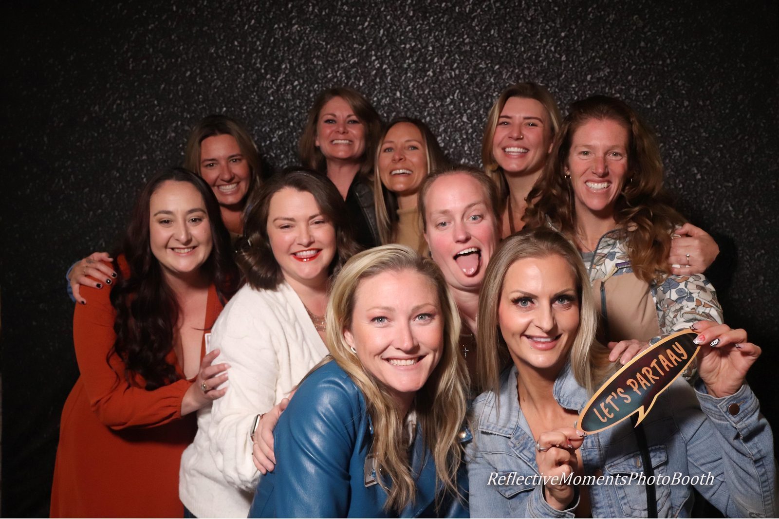 Old friends reuniting and posing at the mirror photo booth at their 20-year high school reunion
